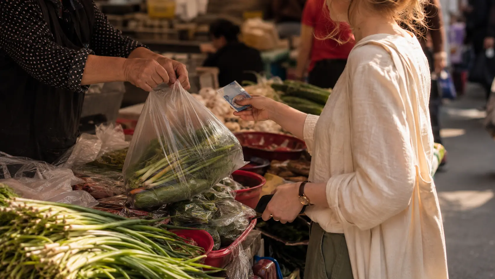 Foreigner holding cash and goods at Korean traditional market stall negotiating price