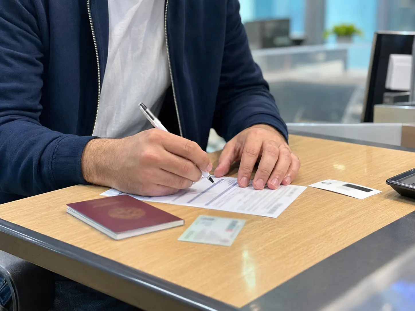Foreigner reviewing bank transfer form at Korean bank branch counter for sending money abroad