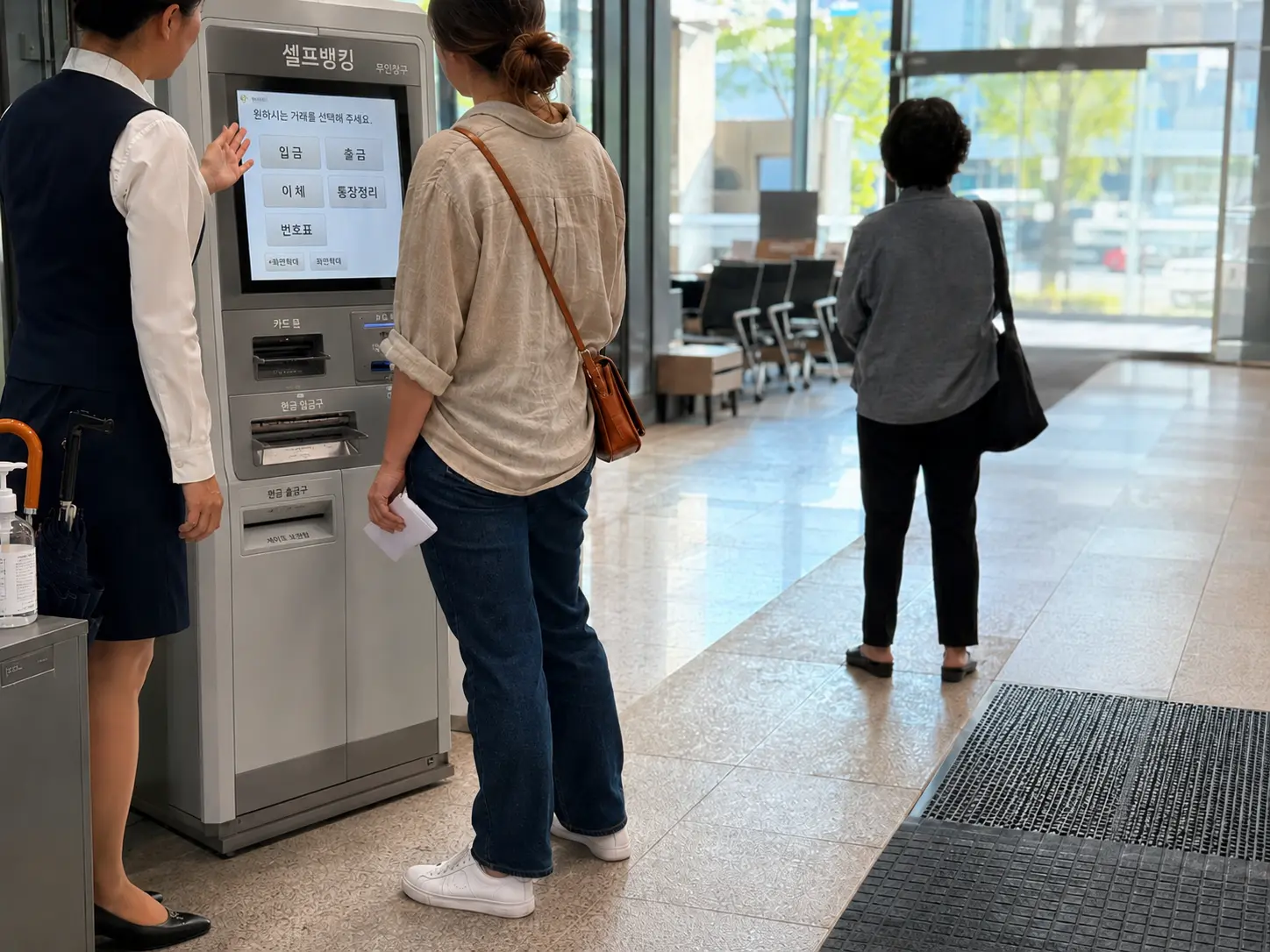 Foreign resident in a beige linen shirt and dark jeans walking past a Korean bank branch entrance in the early morning