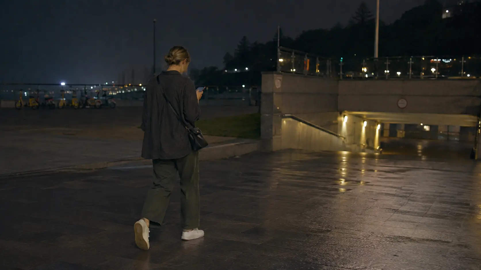 Foreigner checking phone at a Han River park delivery pickup zone at dusk
