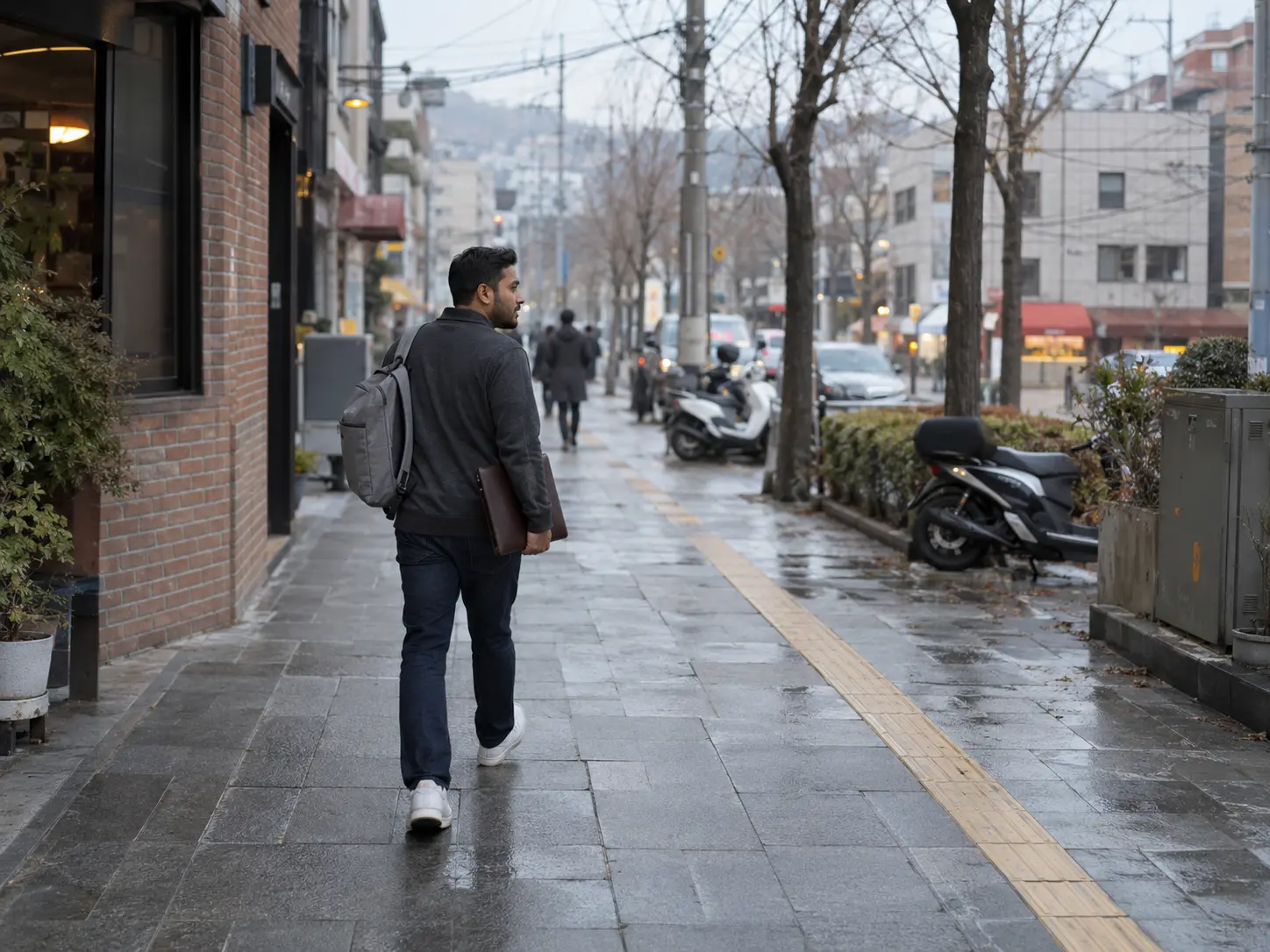 Man in charcoal half-zip pullover and navy jeans holding a document folder on a Korean street while checking pension refund eligibility